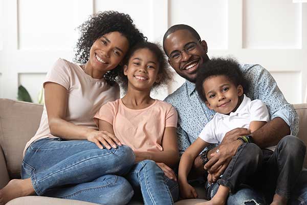 A smiling family of four on couch.